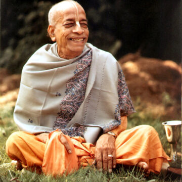 Srila Prabhupada Sitting in a field smiling